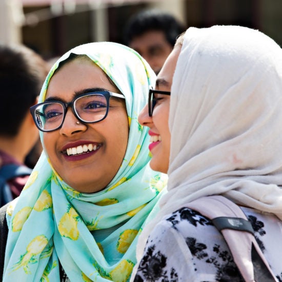 Two students with glasses and headscarves smiling