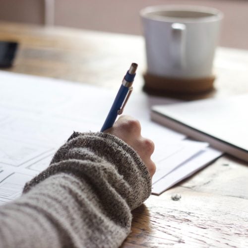 a hand writes in a journal