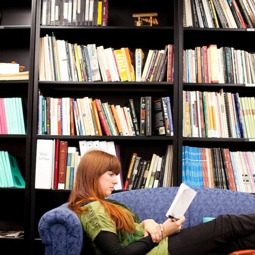 a person reads in front of a bookshelf